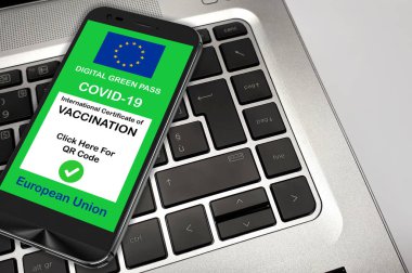 Covid-19 Yeşil Geçit. Avrupa Birliği 'nin dijital yeşil geçiş kartı bir not defterinin klavyesinde akıllı bir telefonun ekranında, Covid-19 için Yeşil Geçit ile çalışırken güvenlik kavramı