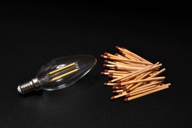 Siyah arka planda kibriti olan bir ampul ışığına yakın plan. Elektrik tedarik sorunu kavramı. karartma