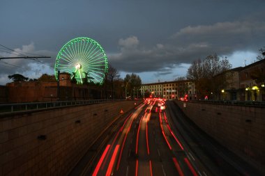 Florence, 5 Aralık 2021. Floransa 'nın merkezindeki bulvarlar boyunca trafik akıyor ve arka planda dönme dolap aydınlatılıyor. İtalya. uzun pozlu çekim