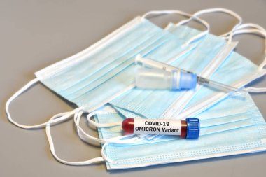 Covid 19 virüsünün yeni Omicron versiyonu. Omicron COVID 19 pozitif test tüpü koruyucu tıbbi maskeler üzerinde kan örneği.