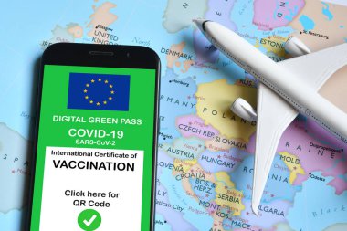 Traveling during the corona virus pandemic. Smartphone with european digital covid-19 vaccination certificate along with protective masks and airplane model on european map. Safe travel concept.