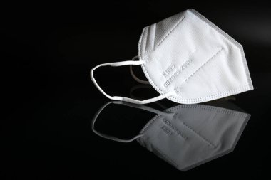 Siyah yansıtıcı arka planda beyaz ffp2 koruyucu maskeyi covid-19 virüsüne karşı yakın plan