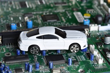 Elektronik panoda oyuncak araba ve mikroçip. Yarı iletken kıtlığı için kavramsal görüntü otomotiv endüstrisinin üretimini bozuyor.