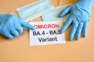 Omicron 'un yeni varyasyonları Covid-19. Doktorun eli mavi eldivende ve beyaz kağıda 