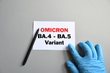 Omicron 'un yeni varyasyonları Covid-19. Doktorun eli mavi eldivende ve beyaz kağıda 