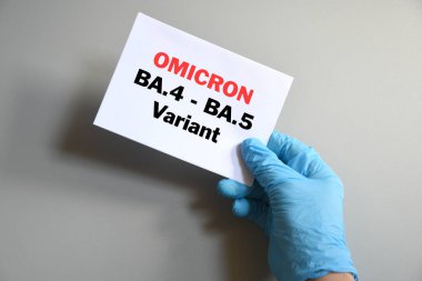 Omicron 'un yeni varyasyonları Covid-19. Doktorun eli mavi eldivende ve beyaz kağıda 