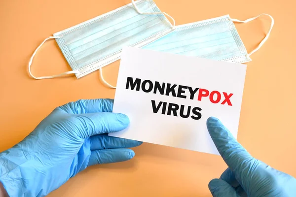 Doctor hand in blue glove indicate Monkeypox Virus words on white paper. Monkeypox on white paper. Medical and Monkeypox virus pandemic concept.