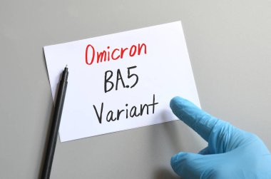 Omicron 'un yeni varyasyonları Covid-19. Doktorun elindeki mavi eldiven beyaz bir çarşafa 