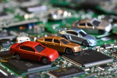 Toy cars on electronic board and microchip. Conceptual image for semiconductor shortage disrupting production of the automotive industry