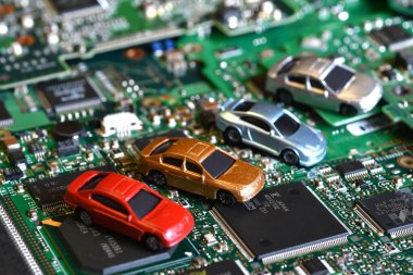Toy cars on electronic board and microchip. Conceptual image for semiconductor shortage disrupting production of the automotive industry