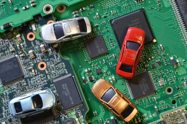 Toy cars on electronic board and microchip. Conceptual image for semiconductor shortage disrupting production of the automotive industry