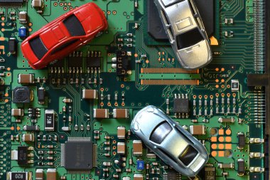Toy cars on electronic board and microchip. Conceptual image for semiconductor shortage disrupting production of the automotive industry