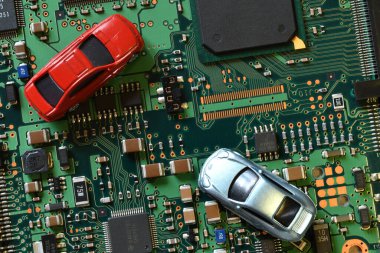 Toy cars on electronic board and microchip. Conceptual image for semiconductor shortage disrupting production of the automotive industry