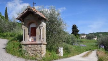 Tabernacle in the Tuscan countryside with olive trees and blue sky. Italy
