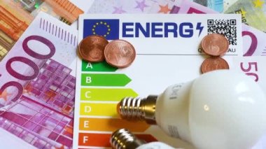 Enerji verimliliği derecelendirme tablosu, Avro banknotlarında ampuller, yakın plan. Enerji fiyatlarına zam kavramı.