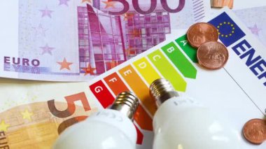 Enerji verimliliği derecelendirme tablosu, Avro banknotlarında ampuller, yakın plan. Enerji fiyatlarına zam kavramı.