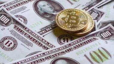 Erkek eli, diğer banknotların yanı sıra bitcoin paralarının yanında yüz dolarlık banknotlar yatırıyor.