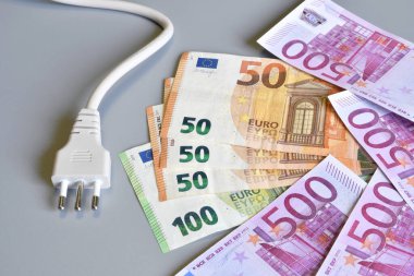 Gri arkaplan üzerinde euro para banknotları olan elektrik prizi. Elektrik maliyetinin artması konsepti. Pahalı enerji faturası ve elektrik fiyatlarındaki artış.