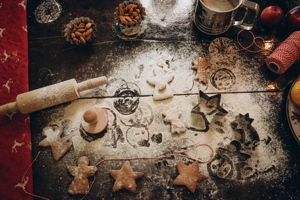 Cibo di Natale. Biscotti fatti in casa di pan di zenzero con ingredienti per la cottura di Natale e utensili da cucina sul tavolo scuro, vista dall'alto Immagine Stock