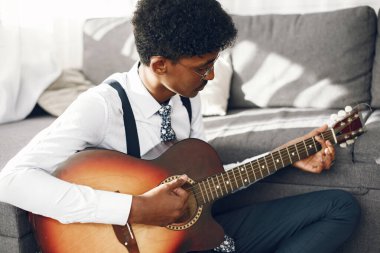 Oturma odasında gitar çalan Hintli adam.