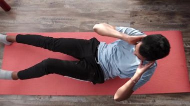 Genç fitness elemanı evde karın kası egzersizi yapıyor.