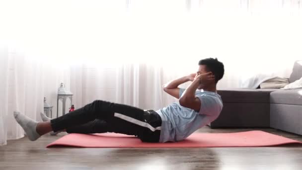 Jonge fitnessman doet buikspieroefeningen thuis — Stockvideo