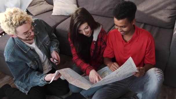 Группа друзей, которые смотрят на карту в светлой комнате — стоковое видео