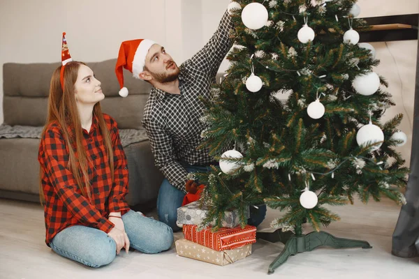 크리스마스 트리 근처 집에 앉아 있는 귀여운 부부 — 스톡 사진