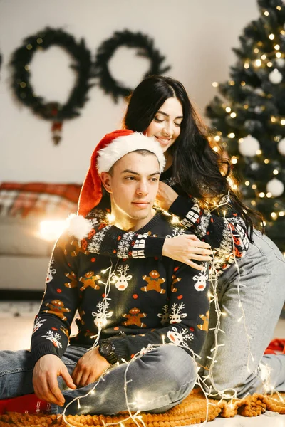 Cute couple sitting at home near christmas tree — Stock Photo, Image