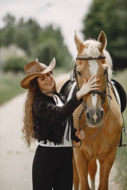 Portrait of woman in brown leather hat with a horse