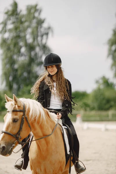 Portrait of woman in black helmet riding a brown horse — Photo