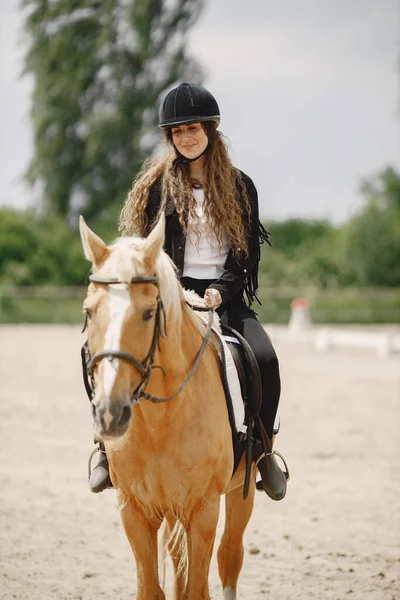 Portrait of woman in black helmet riding a brown horse — Photo
