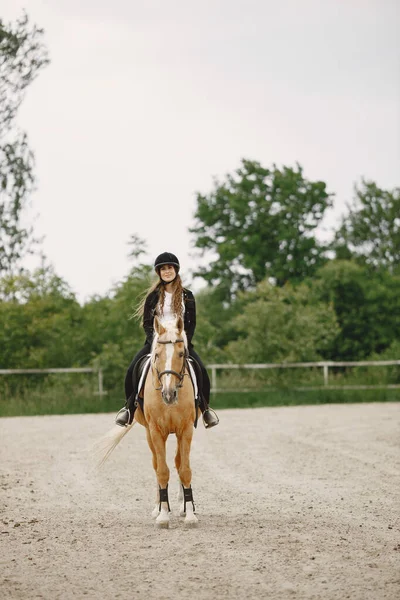 Portrait of woman in black helmet riding a brown horse — 图库照片