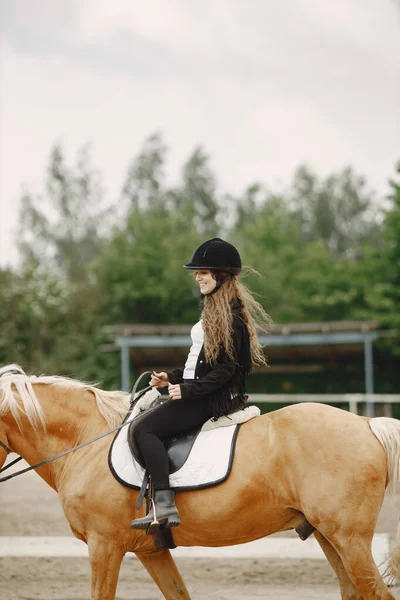 Portrait of woman in black helmet riding a brown horse — Photo