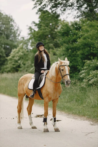 Portrait of woman in black helmet riding a brown horse — Stockfoto