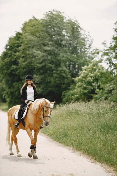 Retrato de mujer en casco negro montando un caballo marrón — Foto de Stock