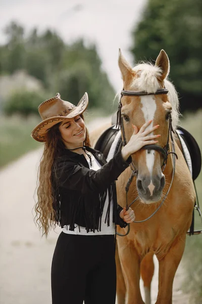 Portrait of woman in brown leather hat with a horse — Stockfoto
