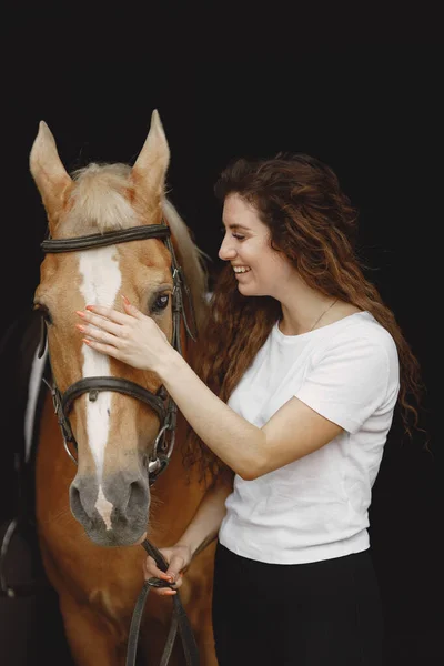 Retrato de mujer jinete con un caballo marrón en un establo — Foto de Stock