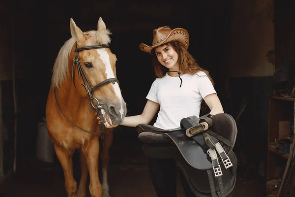 Portrait of rider woman with a brown horse in a stable — Photo