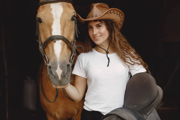 Portrait of rider woman with a brown horse in a stable — Photo