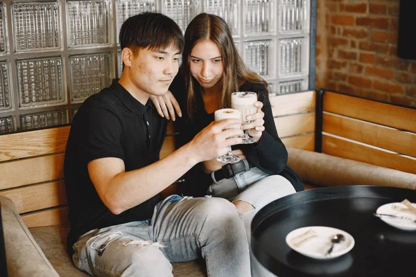 Young couple looking on a cups of cappuccino in a restaurant — Stock fotografie