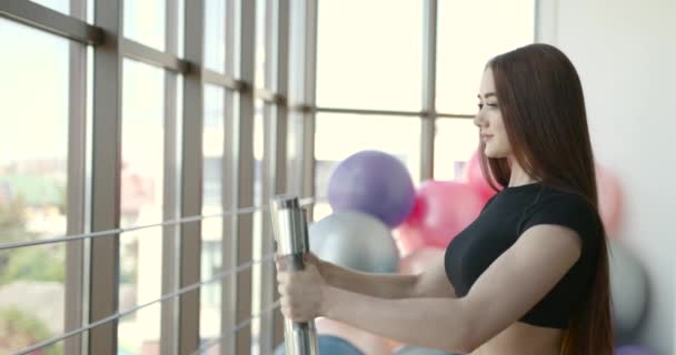 Fit girl in black uniform with dumbbells near window — Wideo stockowe