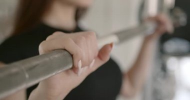 Thoughtful woman leaning on barbell in gym