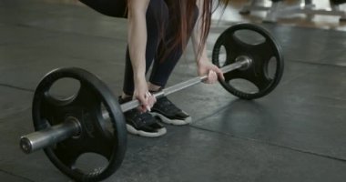 Female athlete doing squats with barbell at gym