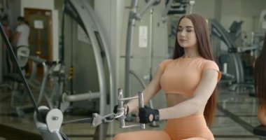 Determined young woman working out on machine