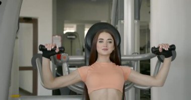 Determined young woman working out on machine
