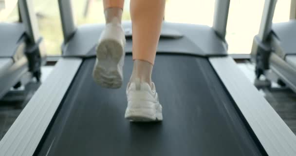 Mujer joven corriendo en la cinta de correr en el gimnasio — Vídeos de Stock