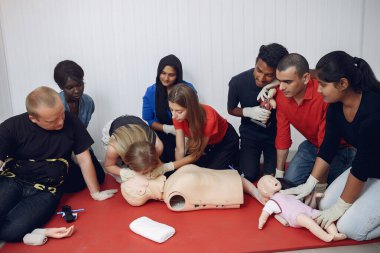Students of different nationalities learn to provide medical care on a mannequin.