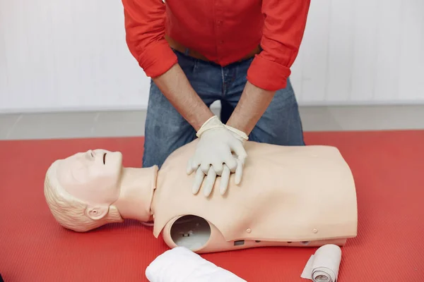 Arabian man learns to do artificial respiration on a mannequin.