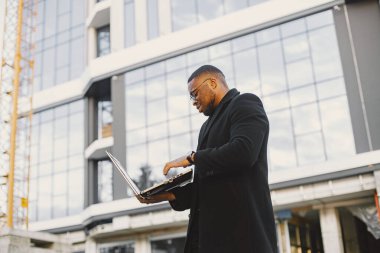 Black race businessman with laptop standing in the city